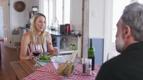 feliz pareja caucásica madura sonriendo, hablando y disfrutando de la comida juntos