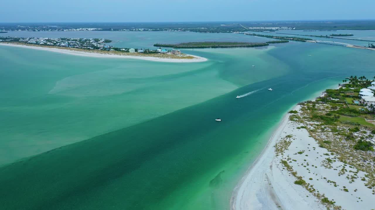 Le barche seguono il canale profondo attraverso Stump Pass verso Manasota Key, sulla costa del Golfo della Florida, tagliando tra banchi di sabbia, piane di marea e ampi gradienti di acqua turchese che si estendono nella Lemon Bay