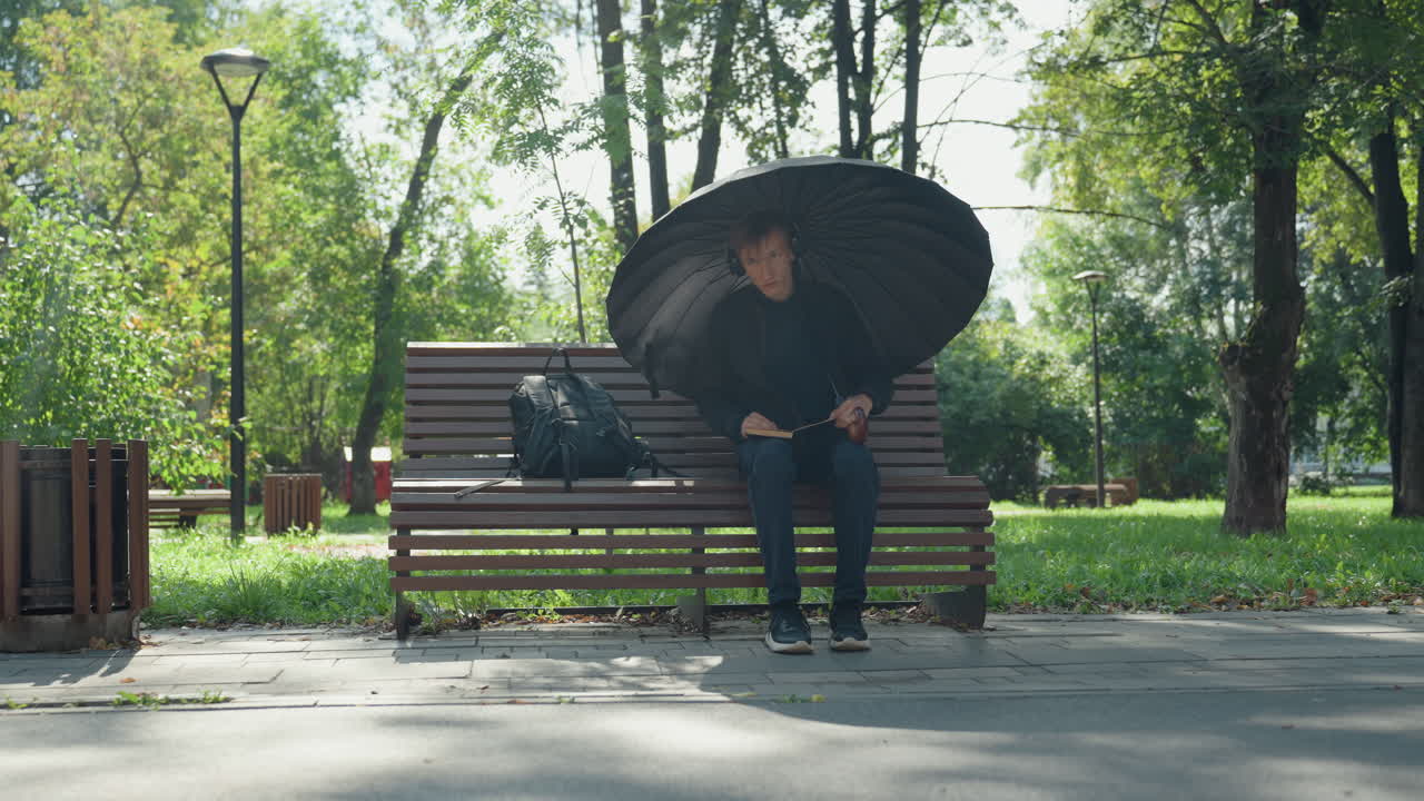 Fredelig øyeblikk i parken, ettertenksom mann i parkens skygger, rolig scene av en mann som hviler stille utendørs, kontemplativ person tar en pause på en fredelig sti under silende sollys og milde skygger i parken