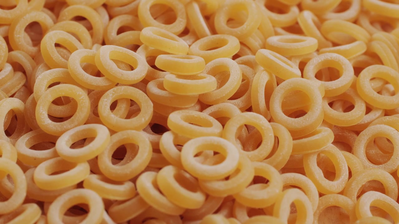 Pasta integrale biologica, maccheroni di semola di grano duro, penne rigate crude in una ciotola di legno. Filmato 4k di alta qualità