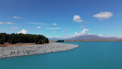 cars crossing stunning blue lake pukaki in new zealand