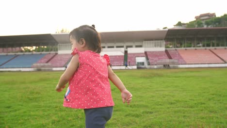 asian little girl running on the grass at stadium