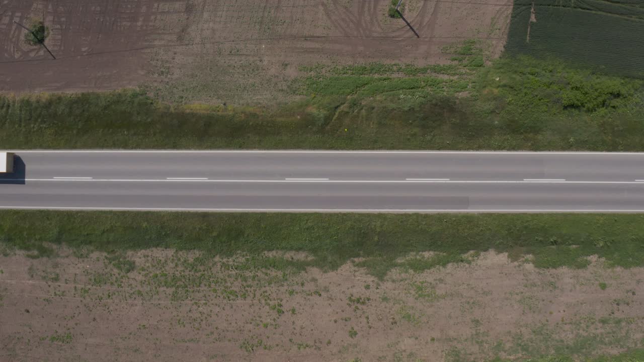 tomada aérea de una furgoneta comercial y un camión de camión en la carretera a través del paisaje rural, directamente por encima del pov del avión no tripulado.