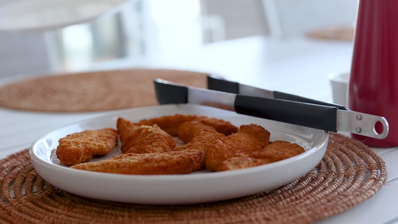 A table is set with a plate of fried chicken, surrounded by a bright, inviting dining environment