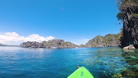 paddling a kayak in azure sea island lagoon between mountains in coron, palawan, philippines