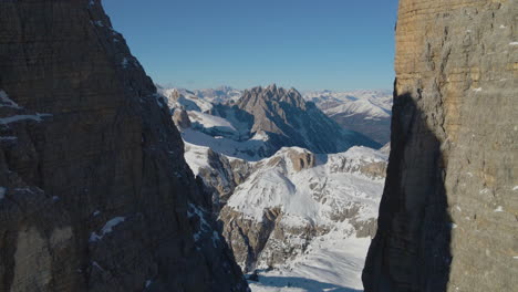 Snowy-mountain-terrain-aerial-view-flying-reverse-through-landmark-Tre-Cime-stone-peaks