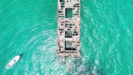 aerial view of shipwreck in turquoise water with boat