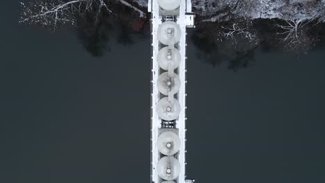 Top-down-tracking-shot-of-cargo-train-crossing-a-steel-bridge-over-river-in-the-Kashubian-District,-Poland