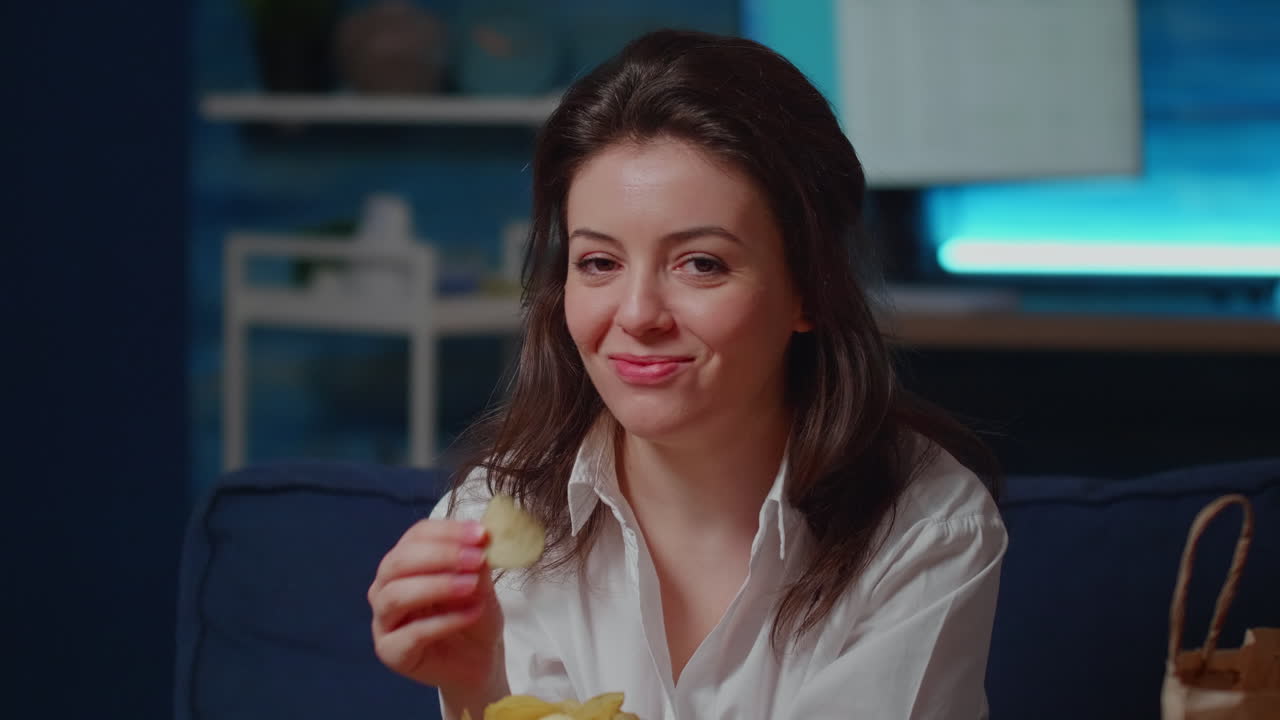 Portrait of young woman sitting in living room eating snack