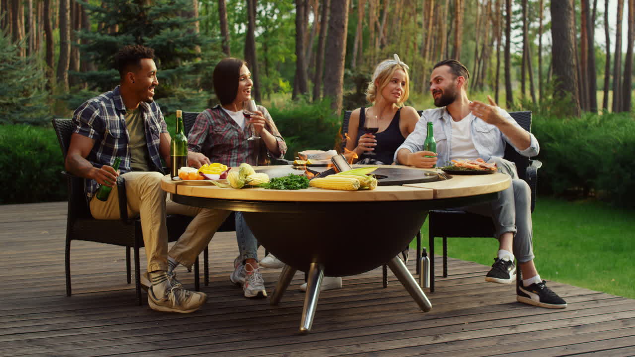 Ragazzi felici che trascorrono il weekend in una foresta estiva. Amici che si rilassano vicino al barbecue.