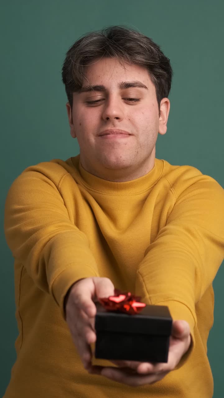 Happy man giving present box in green studio