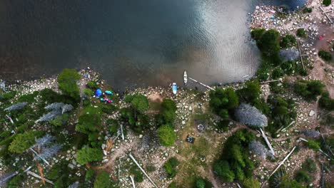 aerial drone top bird's eye view shot of a small lake with pine trees and kayaks docked at shore in northern utah near duchesne county in the uintah national forest on a warm summer day