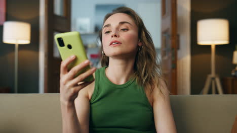 Friendly-girl-calling-cellphone-home-closeup.-Smiling-woman-face-greeting-hand