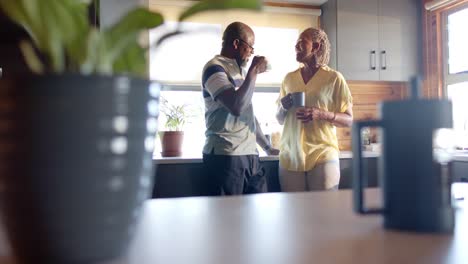 Feliz-Pareja-Afroamericana-Mayor-Tomando-Café-Y-Hablando-En-La-Cocina,-Cámara-Lenta