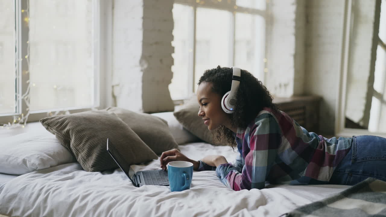 Teenage Girl Relaxing on Bed, Working on Laptop