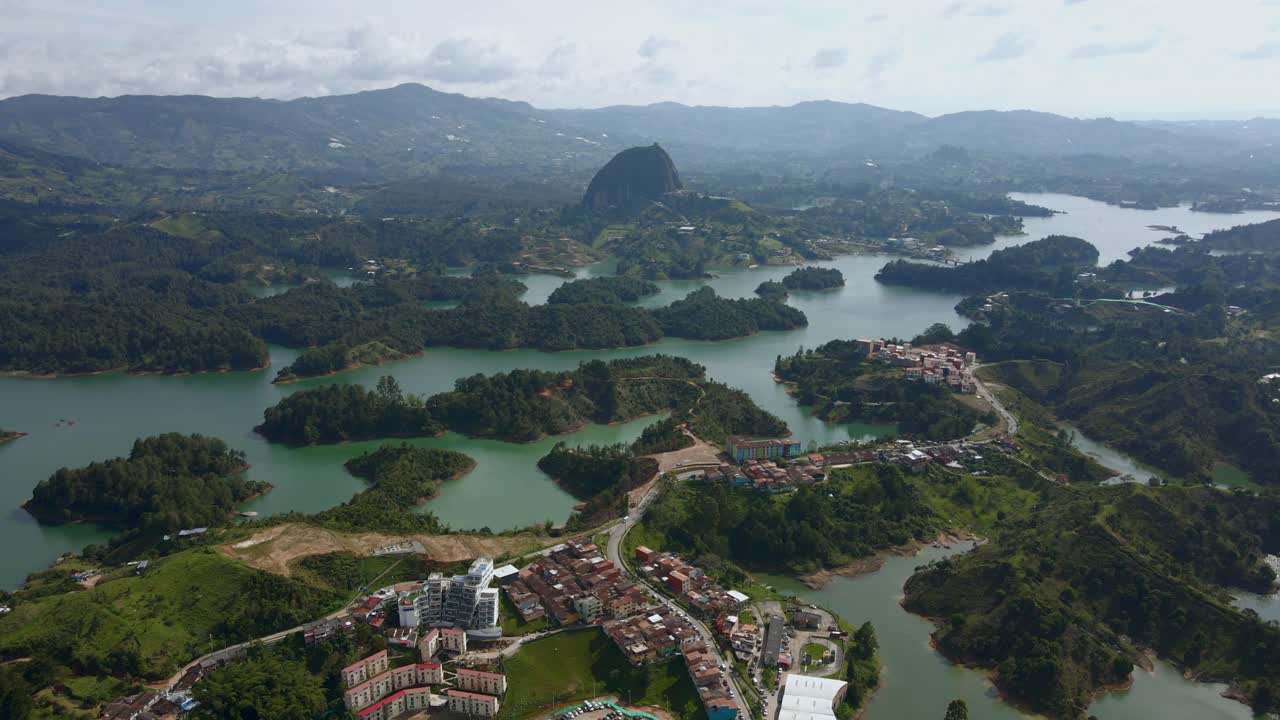 Aerial view of Guatapé reservoir, showcasing vast lake and colorful village in a tropical setting with boats crossing and connecting the islands