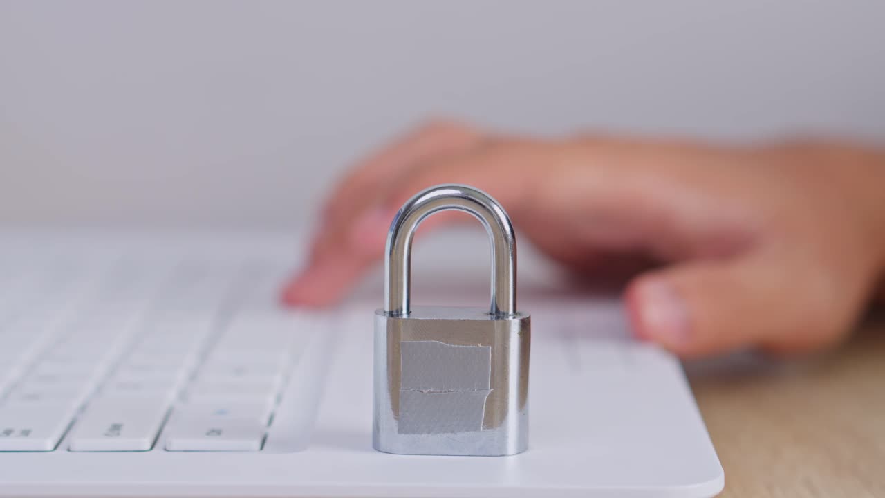 Close-up of locked padlock on laptop while person types in background for Cyber security concept