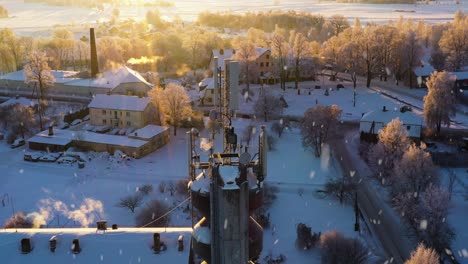 cell tower antenna and smoking chimneys of small town on snowy winter day, aerial view