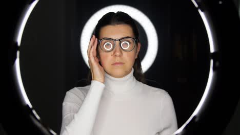 mujer con gafas sobre iluminación blanca en negro