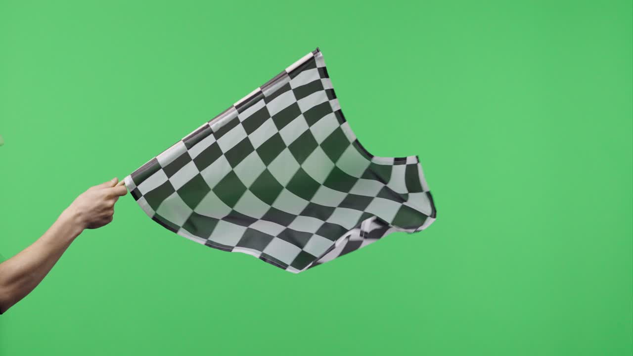손을 들고 녹색 스크린 배경에서 느린 동작으로 체커드 레이스 발을 흔들고 있는 남성 실크 검은색과 색 체커드 발 마무리 시작 레이스 승리, 성취, 성공 및 스포츠 개념