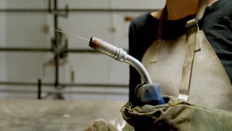 female welder holding blowing torch in workshop 4k