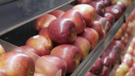 Recoger-A-Mano-Manzanas-Frescas-De-La-Estantería-En-La-Tienda-Del-Supermercado