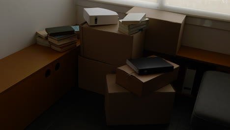 cardboard boxes and books stacked in home interior ready for house relocation moving day