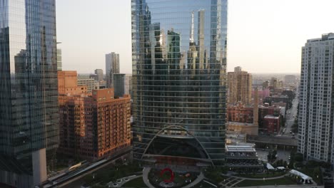 drone flies towards modern skyscraper on river, sunrise