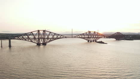 Un-Dron-Disparó-Cruzando-El-Cuarto-Puente-Ferroviario,-En-Queensferry,-Escocia,-Reino-Unido,-Filmado-Al-Atardecer