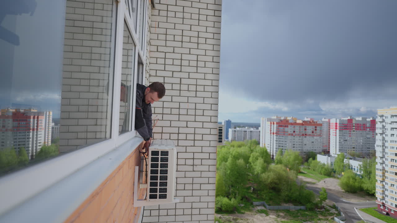 un hombre a gran altitud instala el aire acondicionado. instalación de la unidad externa del sistema de aire acondicionado. refrigeración de aire de verano