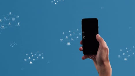 animation of icons over hand of caucasian man holding smarphone on blue background