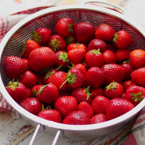 freshly harvested strawberries  metal colander filled with juicy fresh ripe strawberries on an table