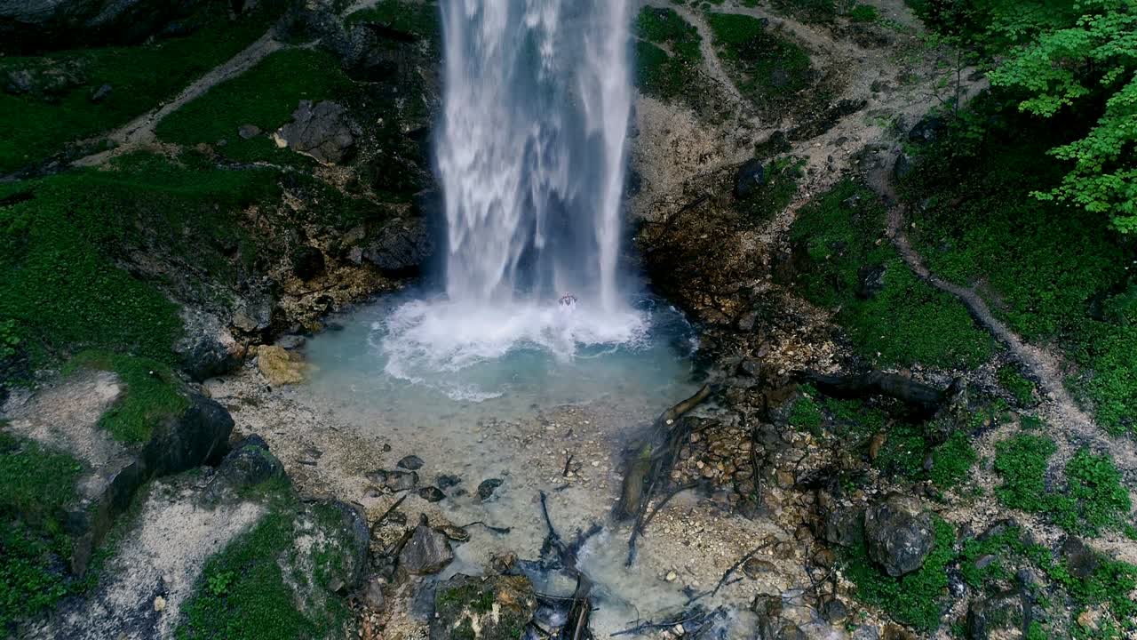 el hombre con barba está haciendo meditación de cascada bajo una gran cascada.
