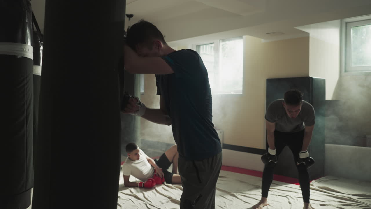 강렬한 권투 세션 후에 휴식을 취하는 남성 운동 선수들의 피곤한 그룹. 운동으로 인한 피로. 스포츠 클럽에서 전투 스포츠를 하고 힘을 향상시니다.