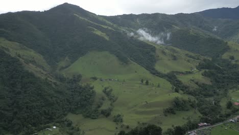 aerial drone panning right above cocora valley mountain peaks clouds hiking town, unpolluted protected national region in salento colombia