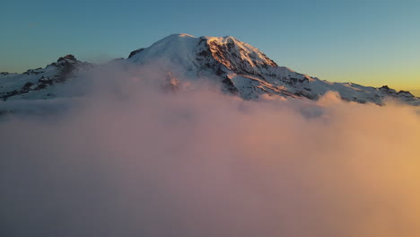 aerial drone view of the mountain summit of mount rainier volcano above the clouds at sunset, beauty in nature