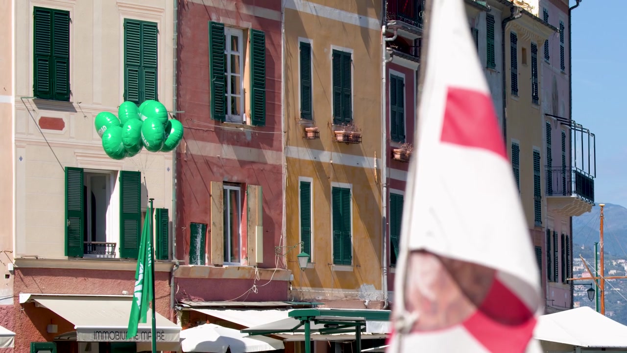 Wapperende vlag voor kleurrijke gebouwen in een Italiaanse kustplaats