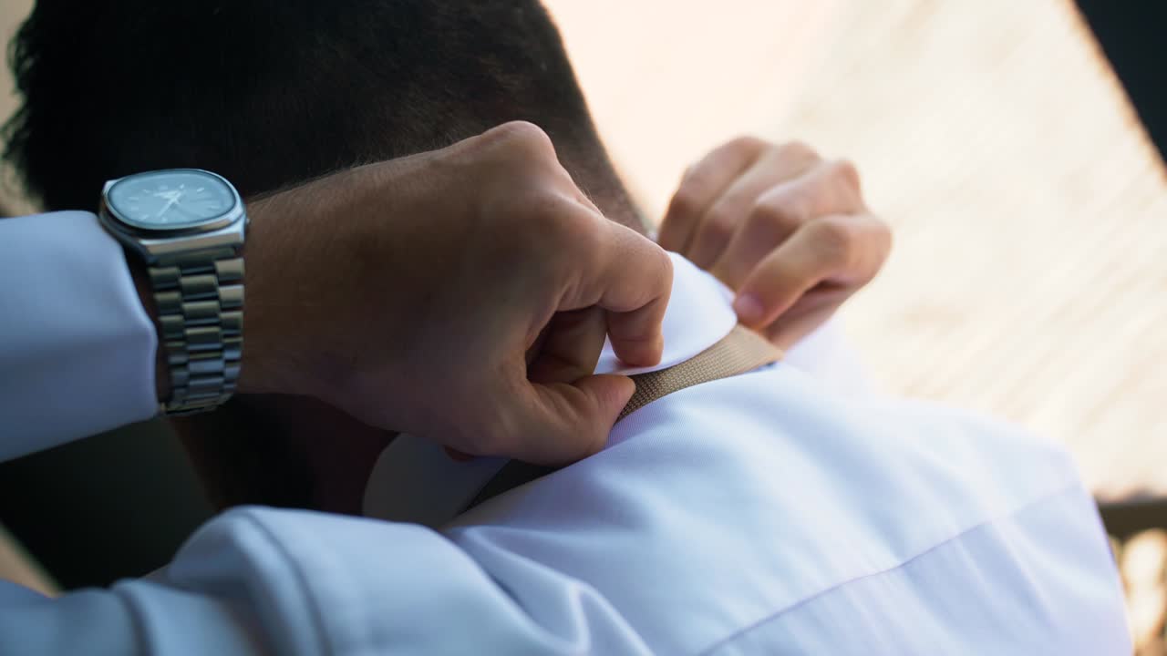 Groom getting ready for the wedding adjusting his tie.
