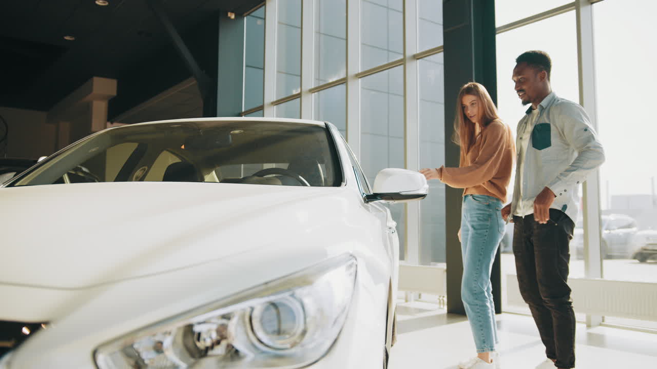 una pareja mirando un coche blanco en un concesionario