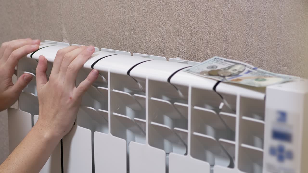 una mujer calienta las manos en una batería en casa en una habitación. 4k. de cerca. cámara lenta