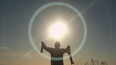 person silhouetted against sunrise/sunset with arms raised