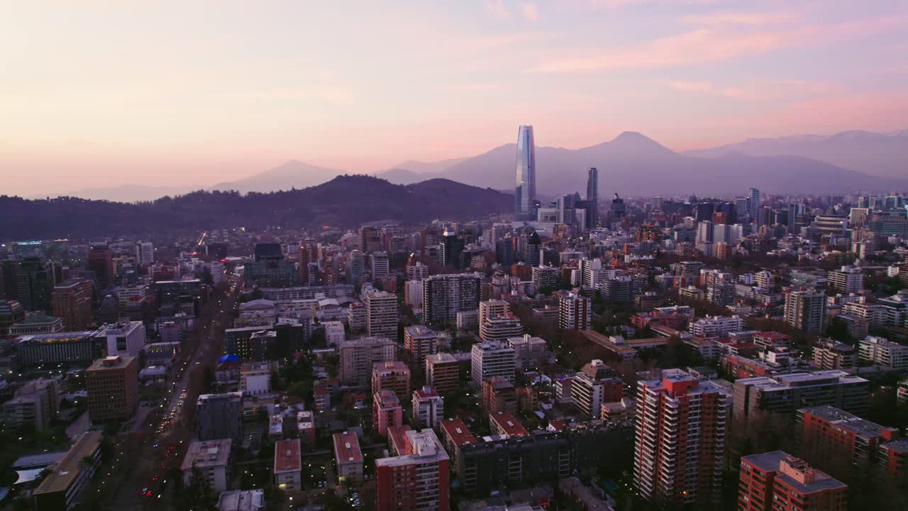 Aerial view establishing Providencia in Santiago Chile with the financial center and the Costanera tower with the mountains at sunset in the background