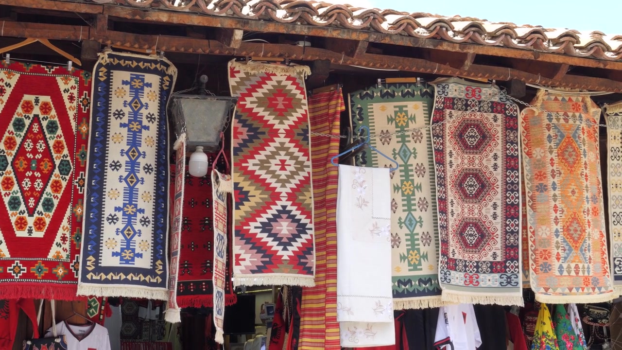 Tkané vlněné koberce kilim a lidové textilie vystavené na stánku na bazaru v Albánii