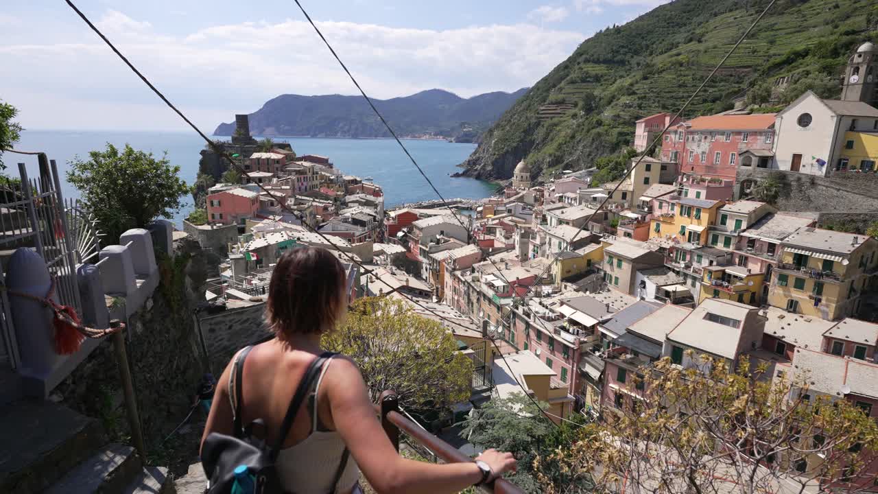 girl looking at one of the beautiful villages with colorful houses in cinque terre, Italy.