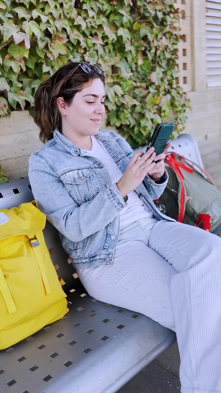 Young Traveler with Yellow Backpack Using Her Phone at a train station platform