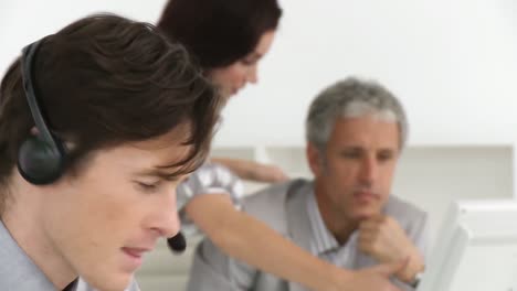 hombre de negocios serio con auriculares y su equipo