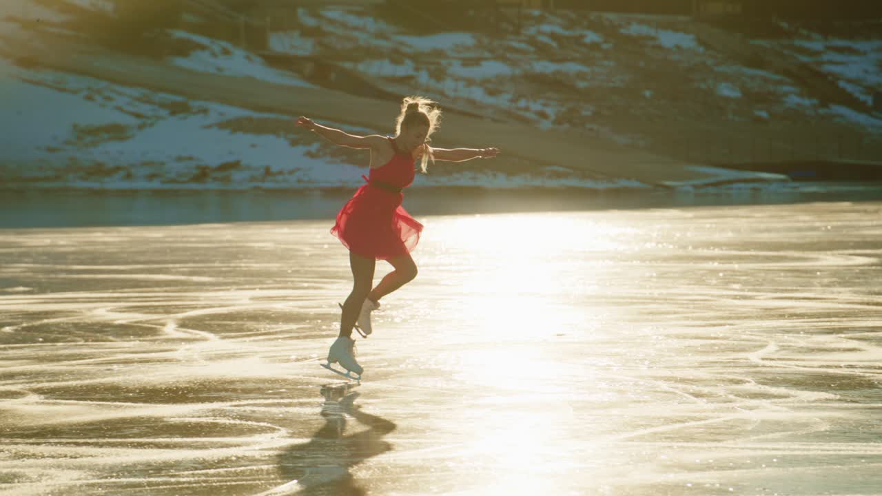 Eine anmutige Eiskunstläuferin in einem roten Kleid tanzt in der Dämmerung über den schimmernden, gefrorenen See und zeigt Eleganz und Freude inmitten einer ruhigen Winterlandschaft