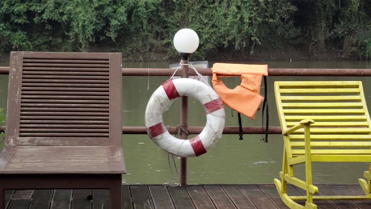 Two loungers on the deck of a floating houseboat, in the background the Khwae River flowing past in Kanchanaburi, Thailand