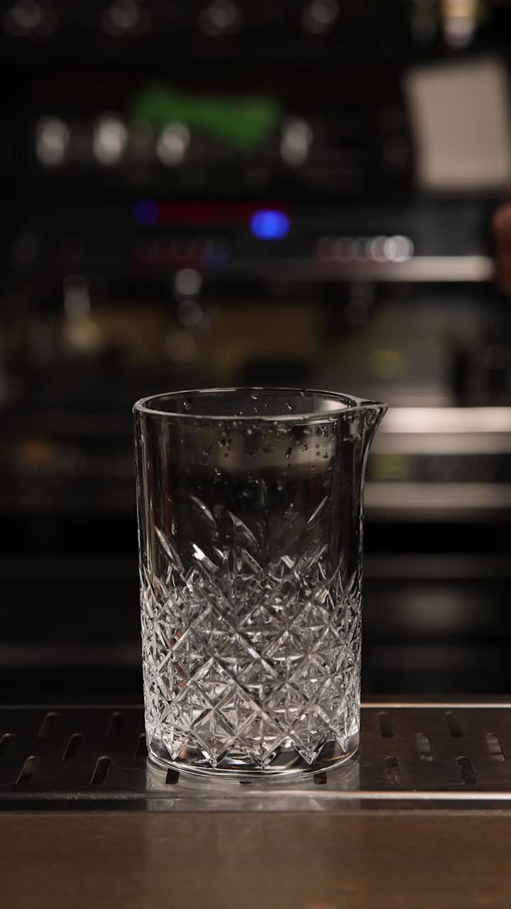Barman che versa liquore in uno shaker per cocktail