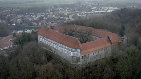 Vista-Aérea-De-Drones-Del-Tradicional-Pueblo-Alemán-Herzberg-Am-Harz-En-El-Famoso-Parque-Nacional-En-Alemania-Central-En-Un-Día-Nublado-En-Invierno.